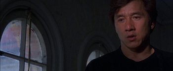 Movie still from “First Strike” (1996), directed by Stanley Tong – A man in a black shirt is looking at the camera; Close Up shot, Over the shoulder angle