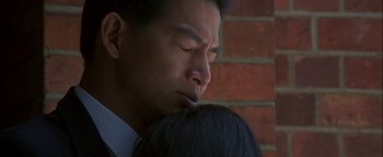 Movie still from “First Strike” (1996), directed by Stanley Tong – A person holding a person's face; Close Up shot, Over the shoulder angle