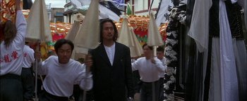 Movie still from “First Strike” (1996), directed by Stanley Tong – A group of people walking down a street holding umbrellas; Medium shot, Low angle