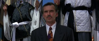 Movie still from “First Strike” (1996), directed by Stanley Tong – A person wearing a suit and tie; Close Up shot, Low angle