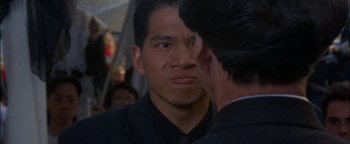 Movie still from “First Strike” (1996), directed by Stanley Tong – A person looking at a person in a suit; Close Up shot, Over the shoulder angle