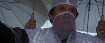 Movie still from “First Strike” (1996), directed by Stanley Tong – A man with a surgical mask on holding an umbrella; Close Up shot, Low angle