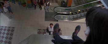 Movie still from “First Strike” (1996), directed by Stanley Tong – A man standing on the stairs of an escalator; Wide shot, High angle