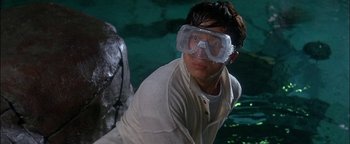 Movie still from “First Strike” (1996), directed by Stanley Tong – A man wearing goggles and a white shirt; Medium shot, Over the shoulder angle