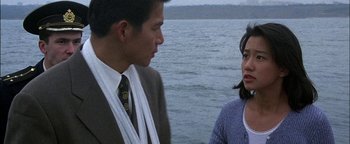 Movie still from “First Strike” (1996), directed by Stanley Tong – A man and a woman standing next to a body of water; Close Up shot, Over the shoulder angle