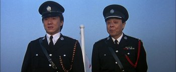 Movie still from “First Strike” (1996), directed by Stanley Tong – Two men in uniform standing next to each other holding a flag; Close Up shot, Low angle