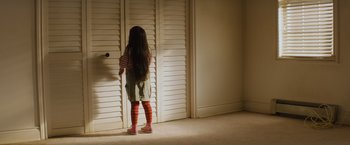 Movie still from “Poltergeist” (2015), directed by Gil Kenan – A little girl standing in front of a door; Wide shot, High angle