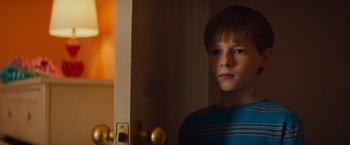 Movie still from “Poltergeist” (2015), directed by Gil Kenan – A boy standing in front of a door looking at the camera; Close Up shot, Over the shoulder angle