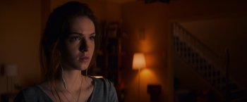 Movie still from “Poltergeist” (2015), directed by Gil Kenan – A young woman with headphones in a dark room; Close Up shot, Over the shoulder angle