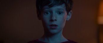 Movie still from “Poltergeist” (2015), directed by Gil Kenan – A young boy with blue eyes stares into the camera; Close Up shot, Low angle