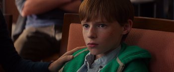 Movie still from “Poltergeist” (2015), directed by Gil Kenan – A young boy sitting in a chair wearing a green sweater; Close Up shot, Over the shoulder angle