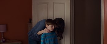 Movie still from “Poltergeist” (2015), directed by Gil Kenan – A young boy and a woman standing next to each other; Close Up shot, Over the shoulder angle