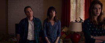 Movie still from “Poltergeist” (2015), directed by Gil Kenan – A woman and a man sitting on a couch in front of a window; Medium shot, Over the shoulder angle