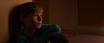 Movie still from “Poltergeist” (2015), directed by Gil Kenan – A young boy sitting in a room with his head tilted to the side; Close Up shot, Low angle