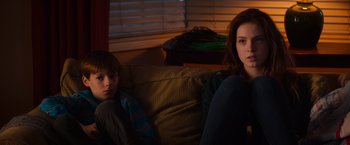 Movie still from “Poltergeist” (2015), directed by Gil Kenan – A woman sitting on a couch next to a young boy; Medium shot, Over the shoulder angle