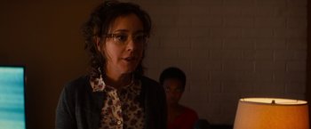 Movie still from “Poltergeist” (2015), directed by Gil Kenan – A woman wearing glasses standing in front of a brick wall; Close Up shot, Over the shoulder angle