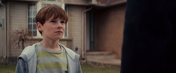 Movie still from “Poltergeist” (2015), directed by Gil Kenan – A young boy standing in front of a house; Close Up shot, Over the shoulder angle