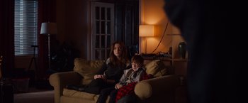 Movie still from “Poltergeist” (2015), directed by Gil Kenan – A woman and a boy sitting on a couch in a living room; Medium shot, Over the shoulder angle