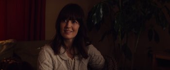 Movie still from “Poltergeist” (2015), directed by Gil Kenan – A woman sitting in a chair smiling for the camera; Close Up shot, Over the shoulder angle