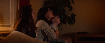 Movie still from “Poltergeist” (2015), directed by Gil Kenan – A group of people sitting on a couch watching television; Medium shot, Low angle