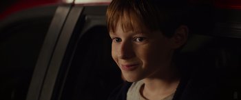 Movie still from “Poltergeist” (2015), directed by Gil Kenan – A young boy with red hair smiling for the camera; Close Up shot, Over the shoulder angle