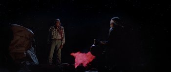 Movie still from “Poltergeist II: The Other Side” (1986), directed by Brian Gibson – A man and a woman standing in front of a fire; Wide shot, Low angle