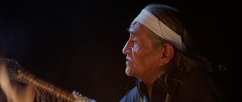 Movie still from “Poltergeist II: The Other Side” (1986), directed by Brian Gibson – An older man with a white headband is looking into the distance; Close Up shot, Over the shoulder angle