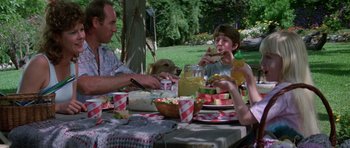 Movie still from “Poltergeist II: The Other Side” (1986), directed by Brian Gibson – A group of people sitting at a picnic table eating watermelon; Medium shot, High angle