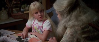 Movie still from “Poltergeist II: The Other Side” (1986), directed by Brian Gibson – A little girl sitting at a table with an older woman; Close Up shot, High angle