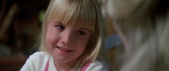 Movie still from “Poltergeist II: The Other Side” (1986), directed by Brian Gibson – A young girl smiling for the camera; Close Up shot, Over the shoulder angle