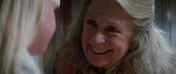 Movie still from “Poltergeist II: The Other Side” (1986), directed by Brian Gibson – An older woman smiling at the camera; Close Up shot, Over the shoulder angle