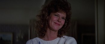 Movie still from “Poltergeist II: The Other Side” (1986), directed by Brian Gibson – A person with curly hair smiling; Close Up shot, Low angle