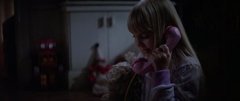 Movie still from “Poltergeist II: The Other Side” (1986), directed by Brian Gibson – A little girl is holding a teddy bear while wearing headphones; Close Up shot, High angle