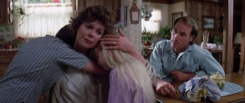 Movie still from “Poltergeist II: The Other Side” (1986), directed by Brian Gibson – Two women and a man sitting at a dining table; Medium shot, Over the shoulder angle