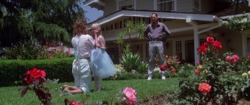 Movie still from “Poltergeist II: The Other Side” (1986), directed by Brian Gibson – A man and a woman standing next to a little girl in front of a house; Wide shot, Low angle