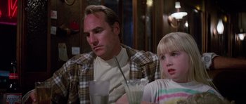 Movie still from “Poltergeist II: The Other Side” (1986), directed by Brian Gibson – A man sitting next to a little girl at a table; Close Up shot, Over the shoulder angle