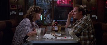 Movie still from “Poltergeist II: The Other Side” (1986), directed by Brian Gibson – A man and a woman sitting at a table with drinks; Medium shot, Over the shoulder angle