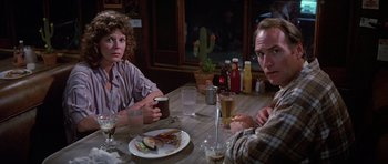 Movie still from “Poltergeist II: The Other Side” (1986), directed by Brian Gibson – A man and a woman sitting at a table with a plate of food; Medium shot, Over the shoulder angle