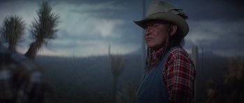 Movie still from “Poltergeist II: The Other Side” (1986), directed by Brian Gibson – An older man wearing a cowboy hat in front of a desert landscape; Medium shot, Low angle