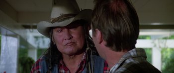 Movie still from “Poltergeist II: The Other Side” (1986), directed by Brian Gibson – An older woman wearing a cowboy hat talking to a younger man; Close Up shot, Over the shoulder angle