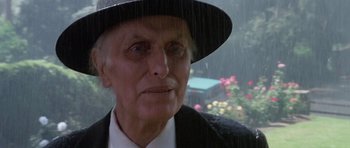 Movie still from “Poltergeist II: The Other Side” (1986), directed by Brian Gibson – An old man wearing a black hat and a black suit; Close Up shot, Low angle