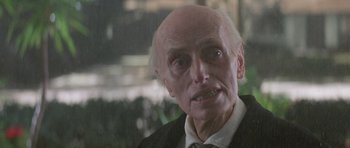 Movie still from “Poltergeist II: The Other Side” (1986), directed by Brian Gibson – An old man with a bald head wearing a suit and tie; Close Up shot, Low angle
