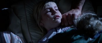Movie still from “Poltergeist II: The Other Side” (1986), directed by Brian Gibson – A little girl laying in a bed with a person touching her face; Close Up shot, High angle