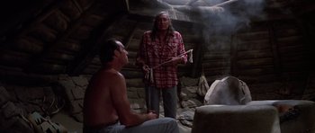 Movie still from “Poltergeist II: The Other Side” (1986), directed by Brian Gibson – A man standing next to another man holding a stick; Medium shot, Over the shoulder angle