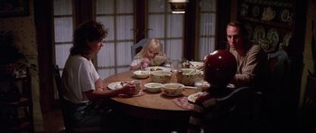 Movie still from “Poltergeist II: The Other Side” (1986), directed by Brian Gibson – A group of people sitting at a table eating food; Medium shot, High angle