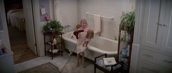 Movie still from “Poltergeist II: The Other Side” (1986), directed by Brian Gibson – A little girl in a bath room holding a hair dryer; Wide shot, High angle
