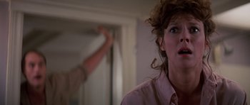 Movie still from “Poltergeist II: The Other Side” (1986), directed by Brian Gibson – A woman in a pink shirt is looking at a mirror; Close Up shot, Over the shoulder angle