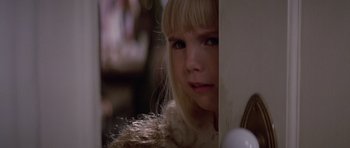 Movie still from “Poltergeist II: The Other Side” (1986), directed by Brian Gibson – A young girl with blonde hair and blue eyes looking at the camera; Close Up shot, Over the shoulder angle