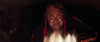 Movie still from “Poltergeist II: The Other Side” (1986), directed by Brian Gibson – An older native american woman with red and white paint on her face; Close Up shot, Over the shoulder angle
