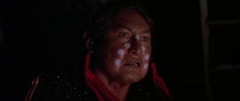 Movie still from “Poltergeist II: The Other Side” (1986), directed by Brian Gibson – An older native american woman with white and red paint on her face; Close Up shot, Low angle